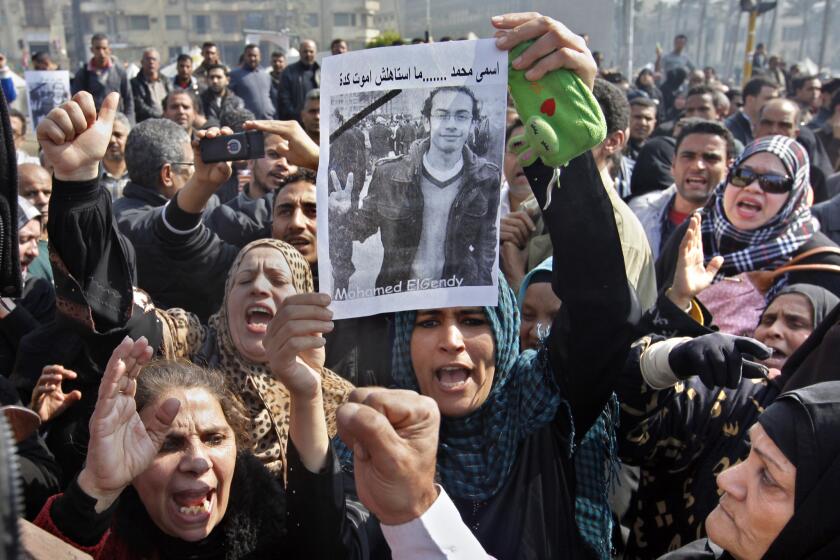 Relatives of Mohamed ElGindy, a 28-year-old Egyptian activist who died of injuries sustained during or after a protest last week, hold up his picture as they shout slogans against President Mohamed Morsi during a funeral procession in Cairo's Tahrir Square.