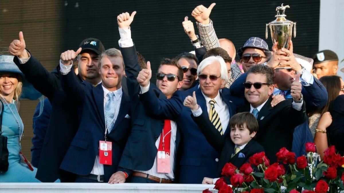 Following American Pharoah's Kentucky Derby win in 2015, Frank Mirahmadi (black hat) celebrates the horse's victory with trainer Bob Baffert, center, from the winner's circle.