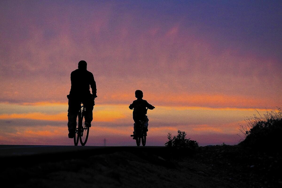 An adult and youngster are silhouetted by the sunset while riding bikes in Azusa on Monday. The drought is being linked to an increase in air pollution this winter.