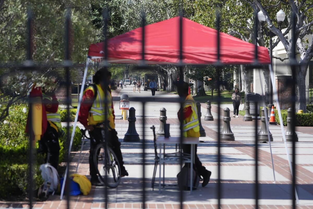 People in yellow vests behind a fence at USC.