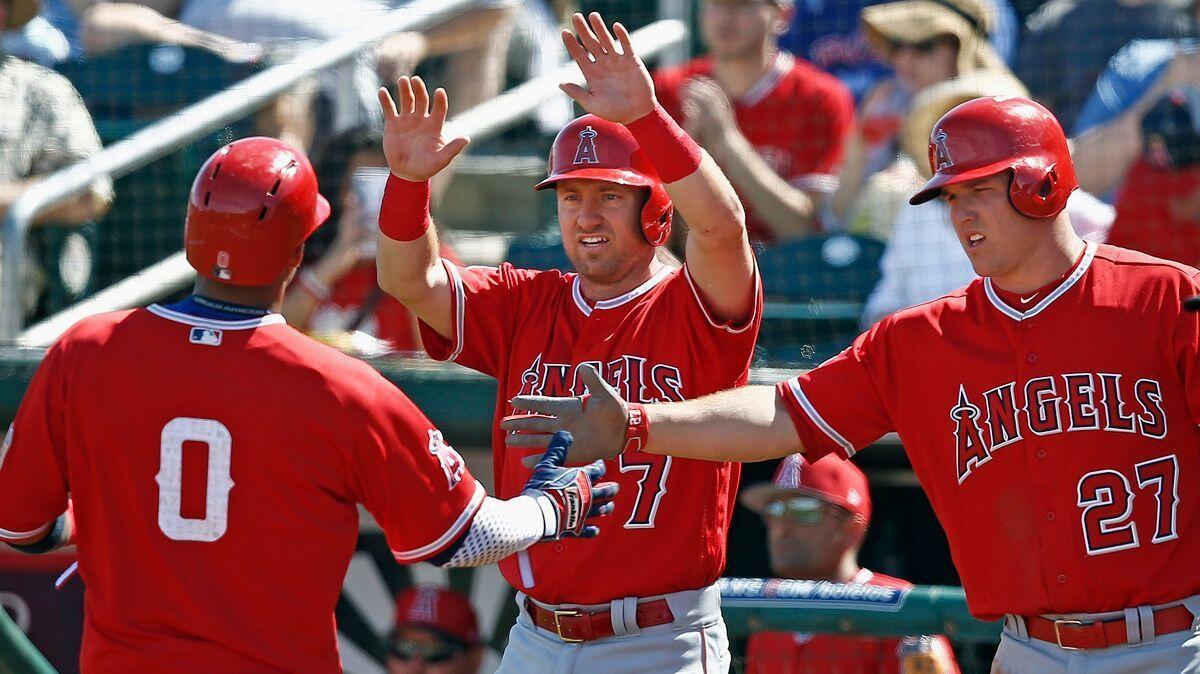 The Angels' Yunel Escobar (0) and Cliff Pennington (7) celebrate scoring with Mike Trout (27) during the second inning of a spring training game Wednesday against the Cincinnati Reds.