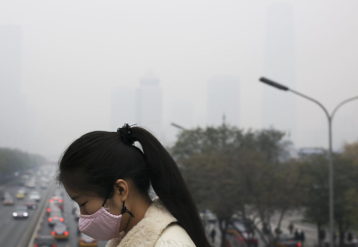 A woman wears a mask to protect herself from pollutants during a hazy day in Beijing on Nov. 19.