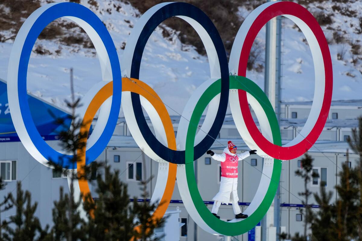 A person stands in the Olympic Rings during a cross-country skiing training session before the 2022 Winter Olympics.