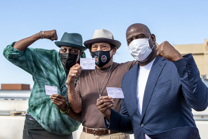 LOS ANGELES, CA - MARCH 24, 2021: Arsenio Hall, left, Danny Trejo and Magic Johnson pose for a photo after they all got vaccine shots on the rooftop of parking structure at USC as a part of a vaccination awareness event at USC on March 24, 2021 in Los Angeles, California. (Gina Ferazzi / Los Angeles Times)