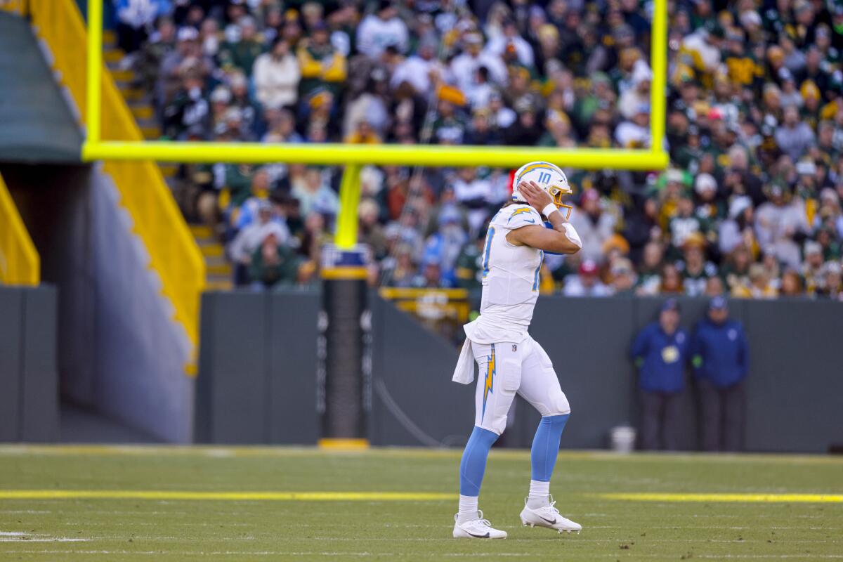 Chargers quarterback Justin Herbert (10) grabs his helmet and walks off field during a road game against the Packers.
