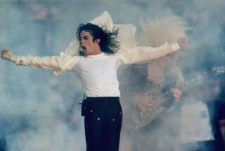 Michael Jackson performs onstage as his white shirt billows in a cloud of smoke.