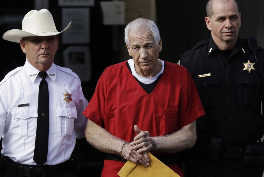 FILE - In this Oct. 9, 2012 file photo, former Penn State University assistant football coach Jerry Sandusky, center, is taken from the Centre County Courthouse by Centre County Sheriff Denny Nau, left, and a deputy, after being sentenced in Bellefonte, Pa. A federal appeals court on Tuesday, Dec. 1, 2020, reinstated former Penn State President Graham Spanier's conviction for child endangerment over his handling of a report that former assistant football coach Jerry Sandusky had sexually abused a boy in a football team shower. (AP Photo/Matt Rourke, File)