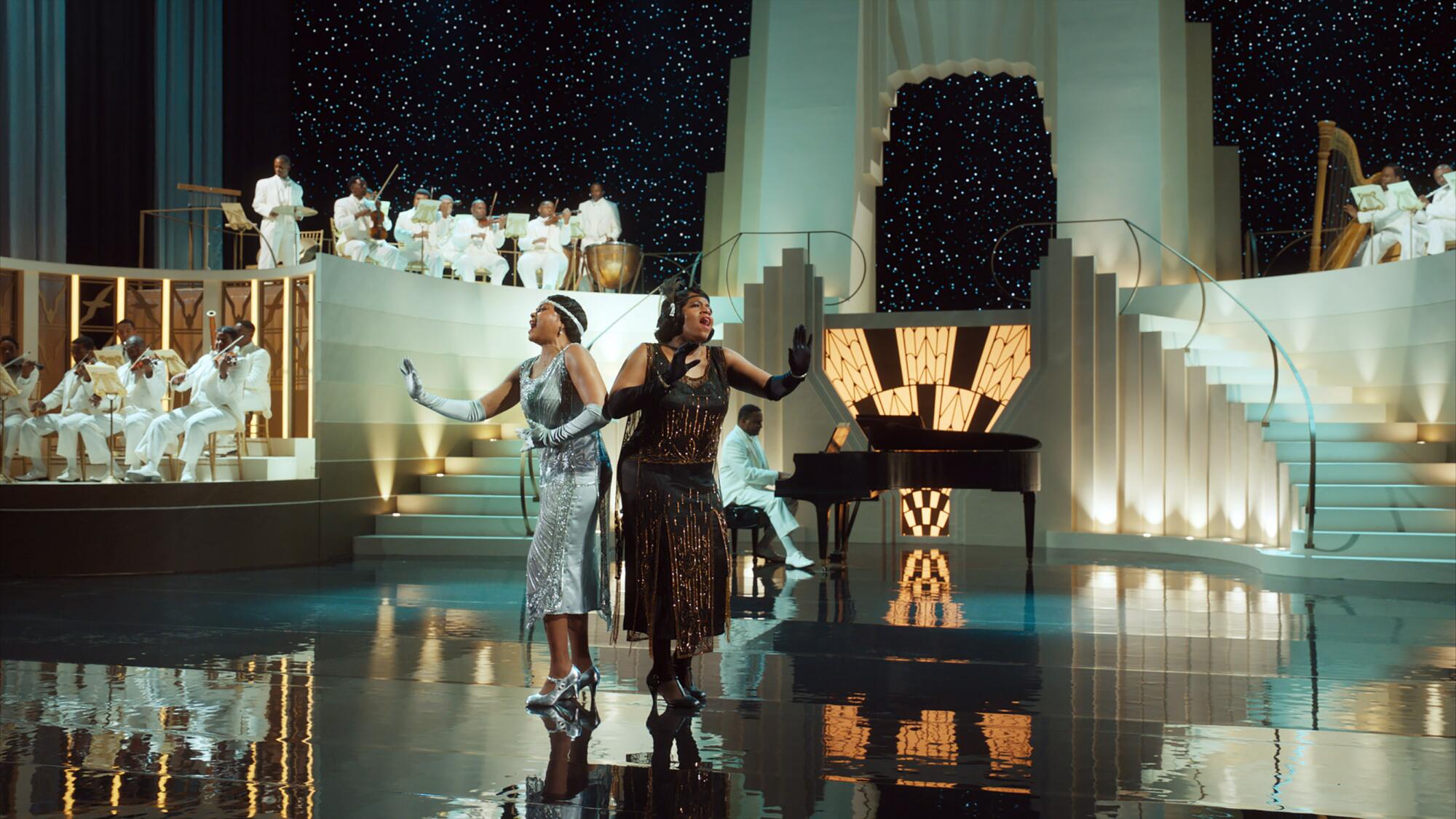 Two women perform on a giant Art Deco set.