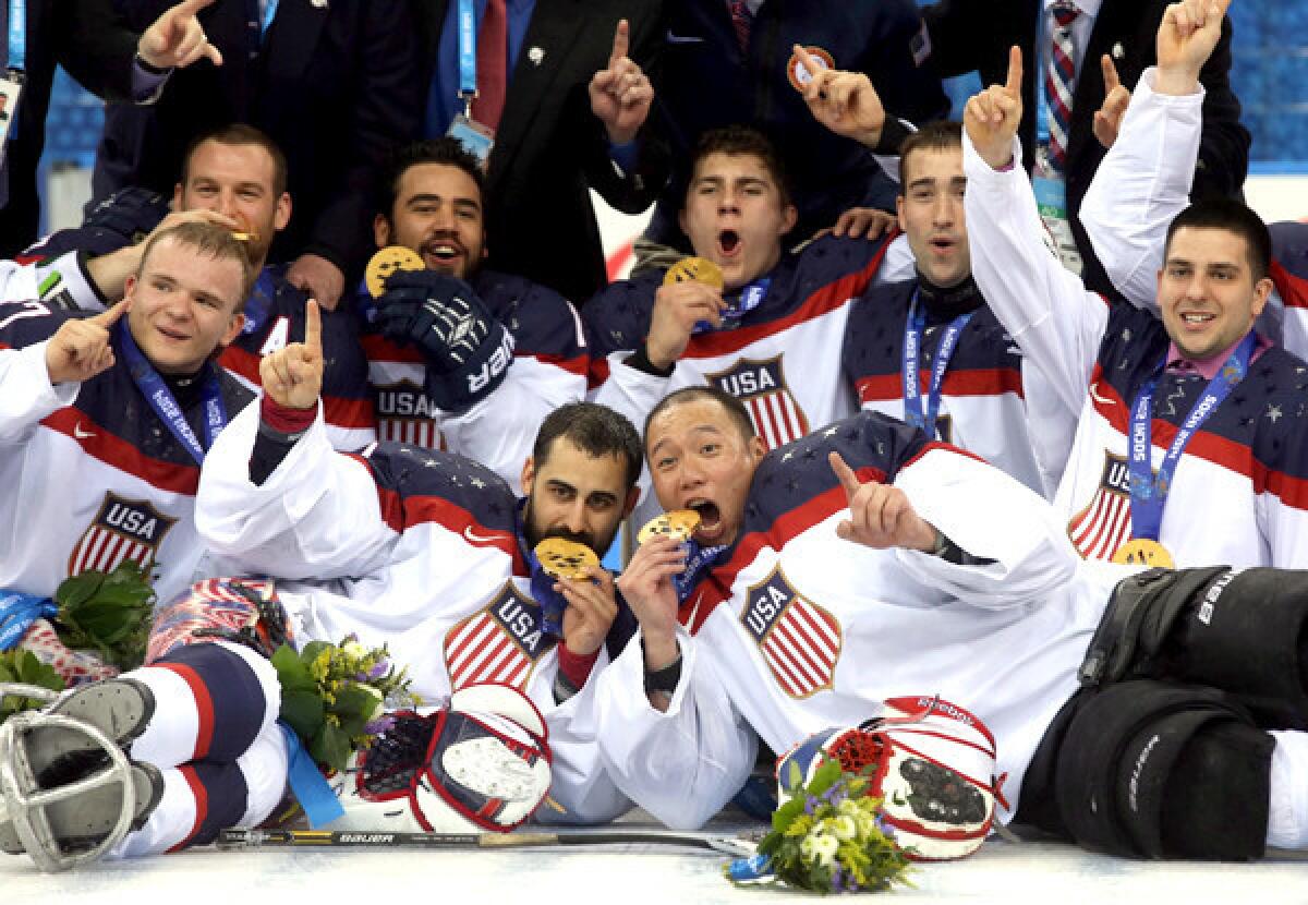 Members of the U.S. hockey team pose for photos after winning the gold medal in sled hockey at the Paralympic Games on Saturday in Sochi, Russia.
