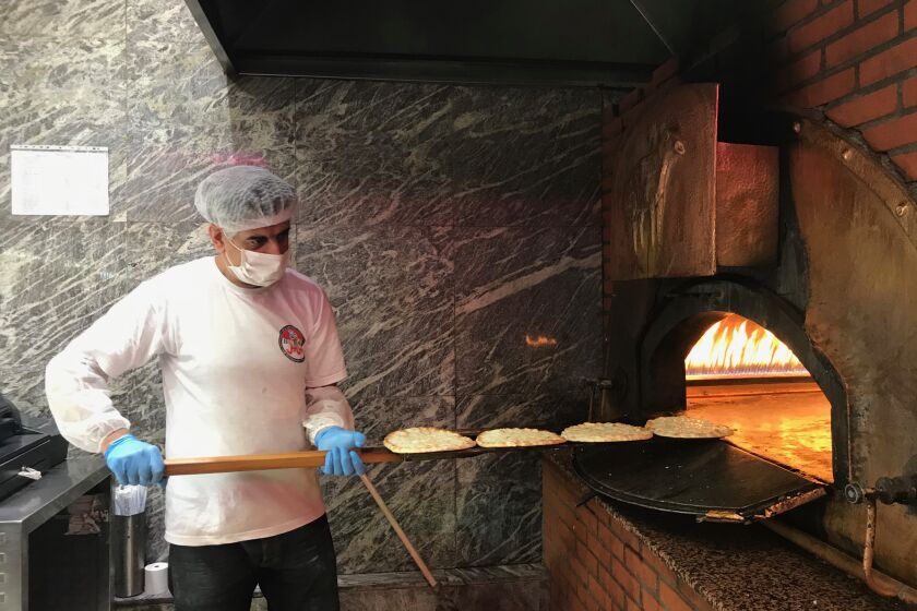 Kamal, one of Barbar's employees, tends to the fire-brick oven while making Manousheh, a Lebanese flatbread pizza