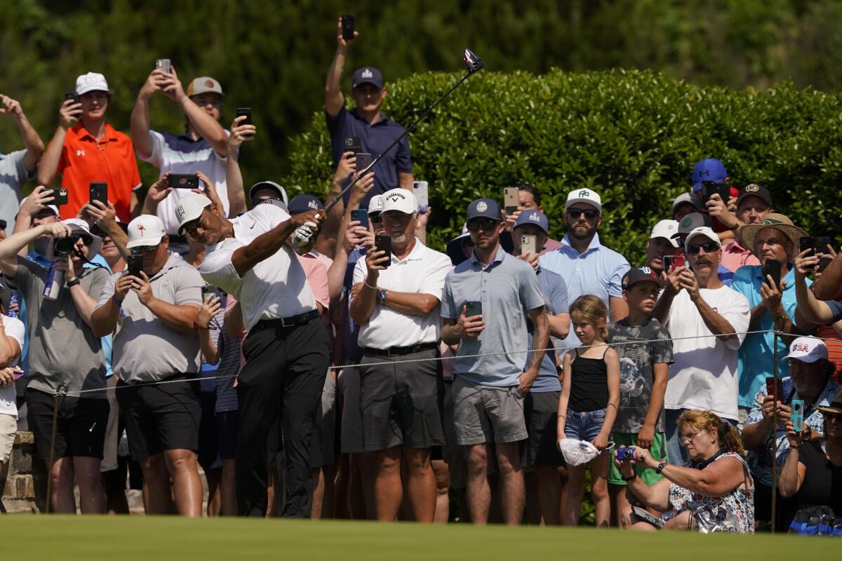 Fans watch Tiger Woods on the seventh hole during a practice round for the PGA Championship golf tournament, Wednesday, May 18, 2022, in Tulsa, Okla. (AP Photo/Matt York)