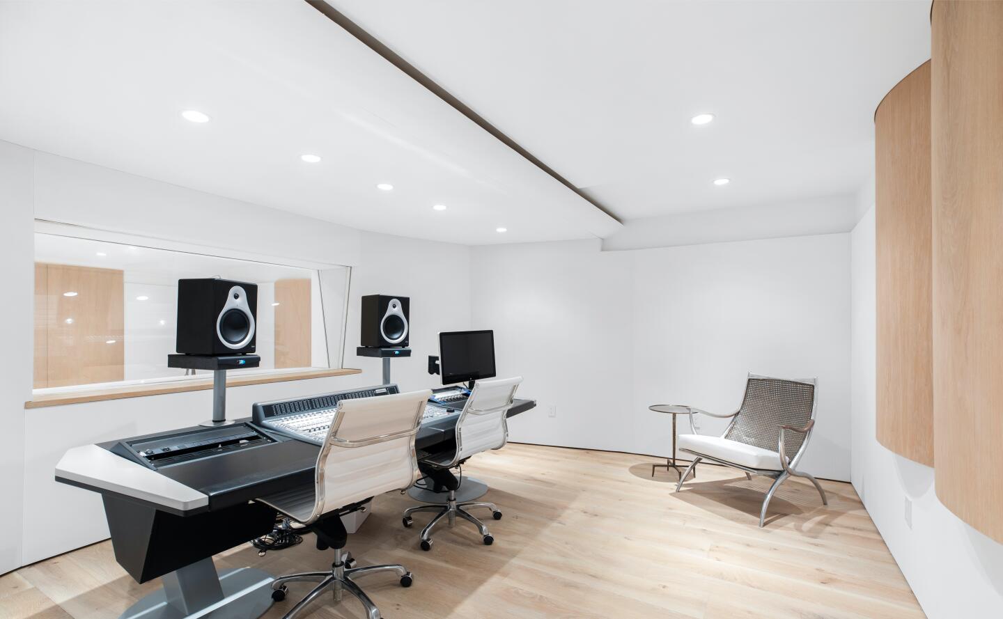White walled recording studio with recording equipment and chairs.