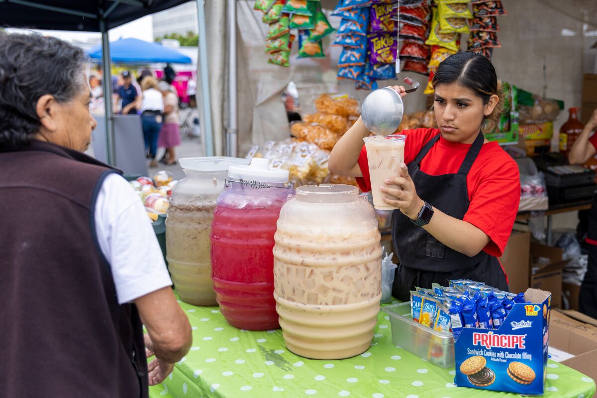 Ana Callejas pours horchata for a customer during the Fiestas Patrias carnival at the Anaheim Indoor Marketplace.