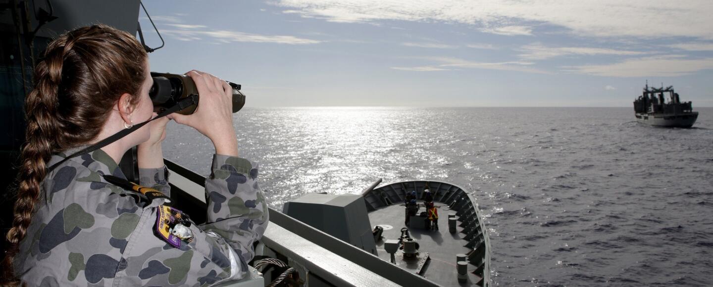 Lieutenant Raina Taggart uses the range finder binoculars to gauge the distance to HMAS Success from the starboard bridge wing of HMAS Toowoomba prior to conducting a Replenishment at Sea during the search for the missing Malaysia Airways Flight MH370.