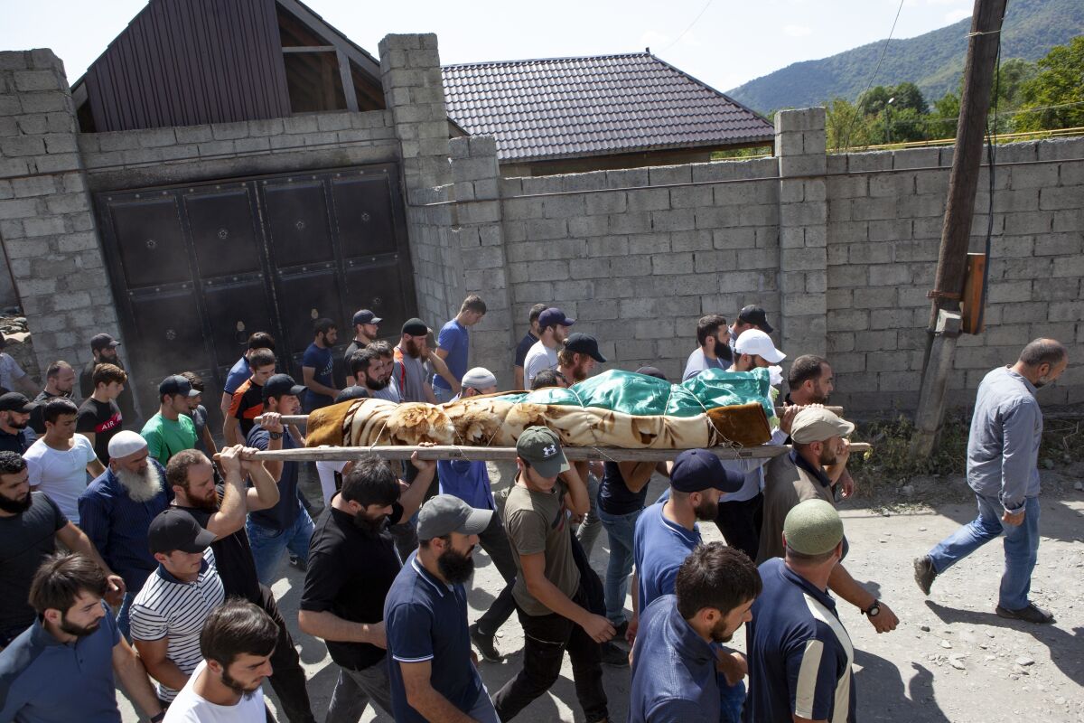 FILE - People carry the body of the victim who has been identified as Zelimkhan Khangoshvili, a Georgian Muslim during the funeral in Duisi village, the Pankisi Gorge valley, in Georgia, Aug. 29, 2019. A Berlin court will deliver its verdict Wednesday, Dec. 15, 2021 in the trial of a Russian man accused of a killing in the German capital two years ago that prosecutors say was ordered by Russia. The slaying of Zelimkhan “Tornike” Khangoshvili, a 40-year-old Georgian citizen of Chechen ethnicity, sparked outrage in Germany and prompted the government to expel two Russian diplomats — and a reciprocal response by Moscow.(AP Photo/Zurab Tsertsvadze, file)