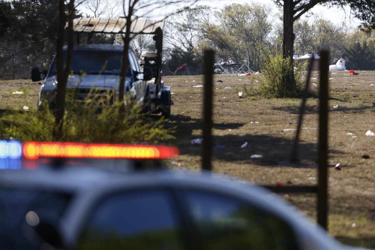 A police car sits in front of the scene, Sunday, April, 3, 2022, where a man was fatally shot and at least 11 other people were injured in connection to a shooting Saturday night at a concert in Dallas, Texas. (Rebecca Slezak/The Dallas Morning News via AP)
