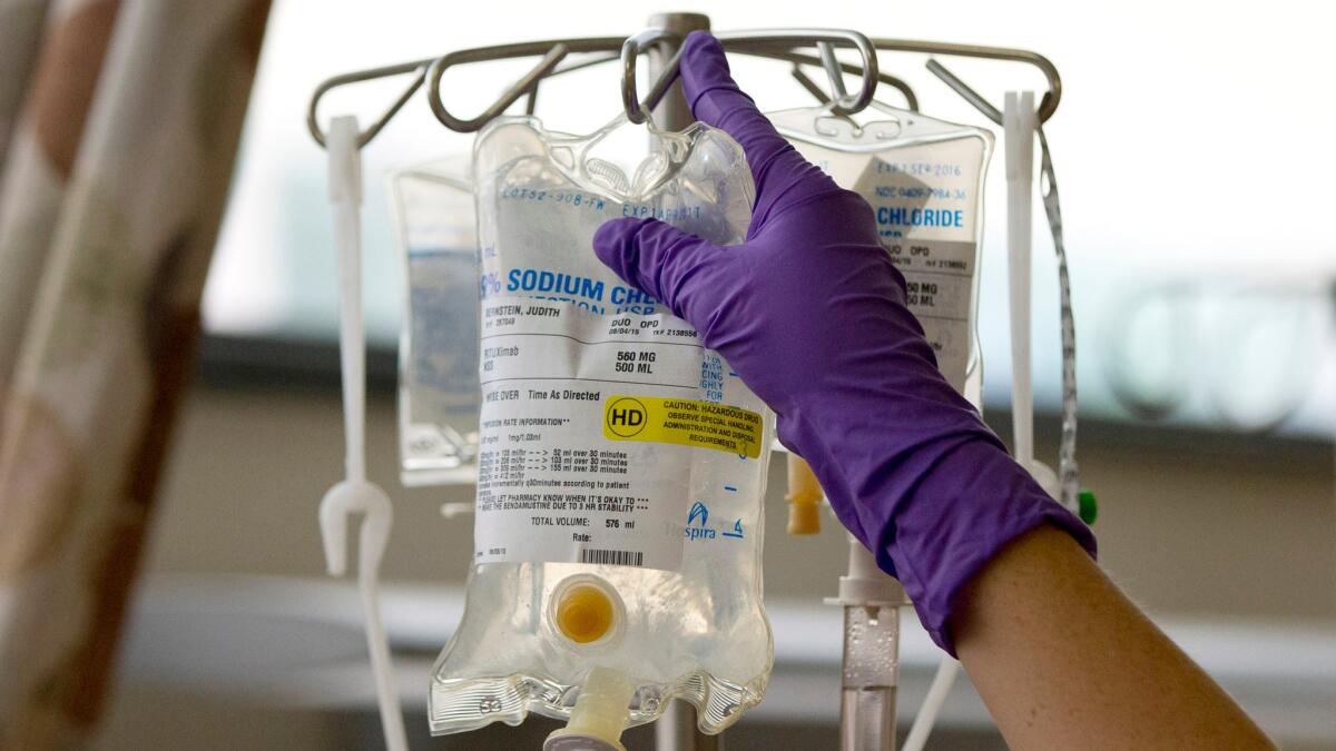 A nurse places a patient's chemotherapy medication on an intravenous stand.