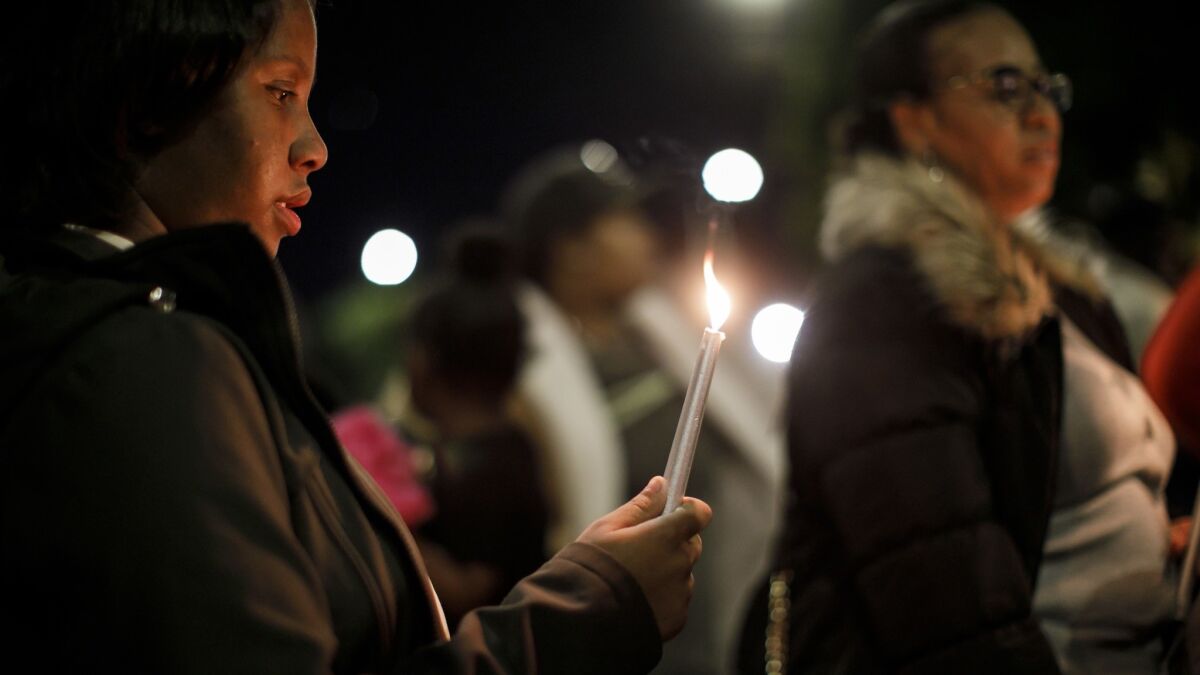 Amirah Muhammad holds a candle during a vigil Wednesday for her mother, Denise Harlins.