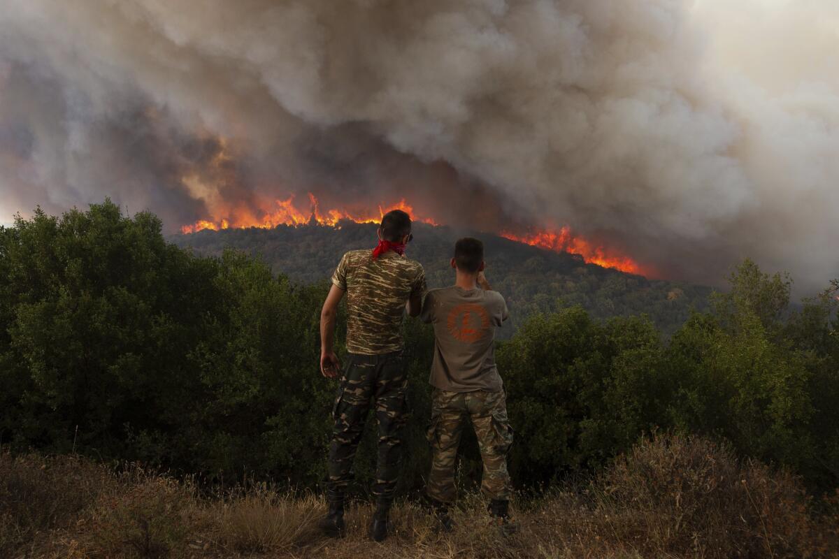 Two people looking out at a forest fire in Greece