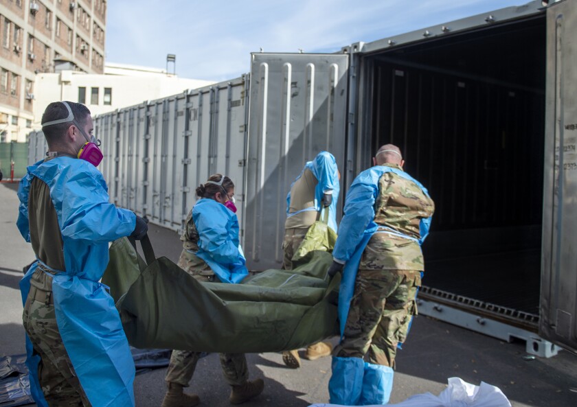 This photo provided by the LA County Dept. of Medical Examiner-Coroner shows National Guard assisting with processing Covid-19 deaths and placing them into temporary storage at LA County Medical Examiner-Coroner Office in Los Angeles on Tuesday, Jan. 12, 2021 in Los Angeles. More than 500 people are dying each day in California because of the coronavirus. The death toll has prompted state officials to send more refrigerated trailers to local governments to act as makeshift morgues. State officials said Friday they have helped distribute 98 refrigerated trailers to help county coroners store dead bodies. (LA County Dept. of Medical Examiner-Coroner via AP)