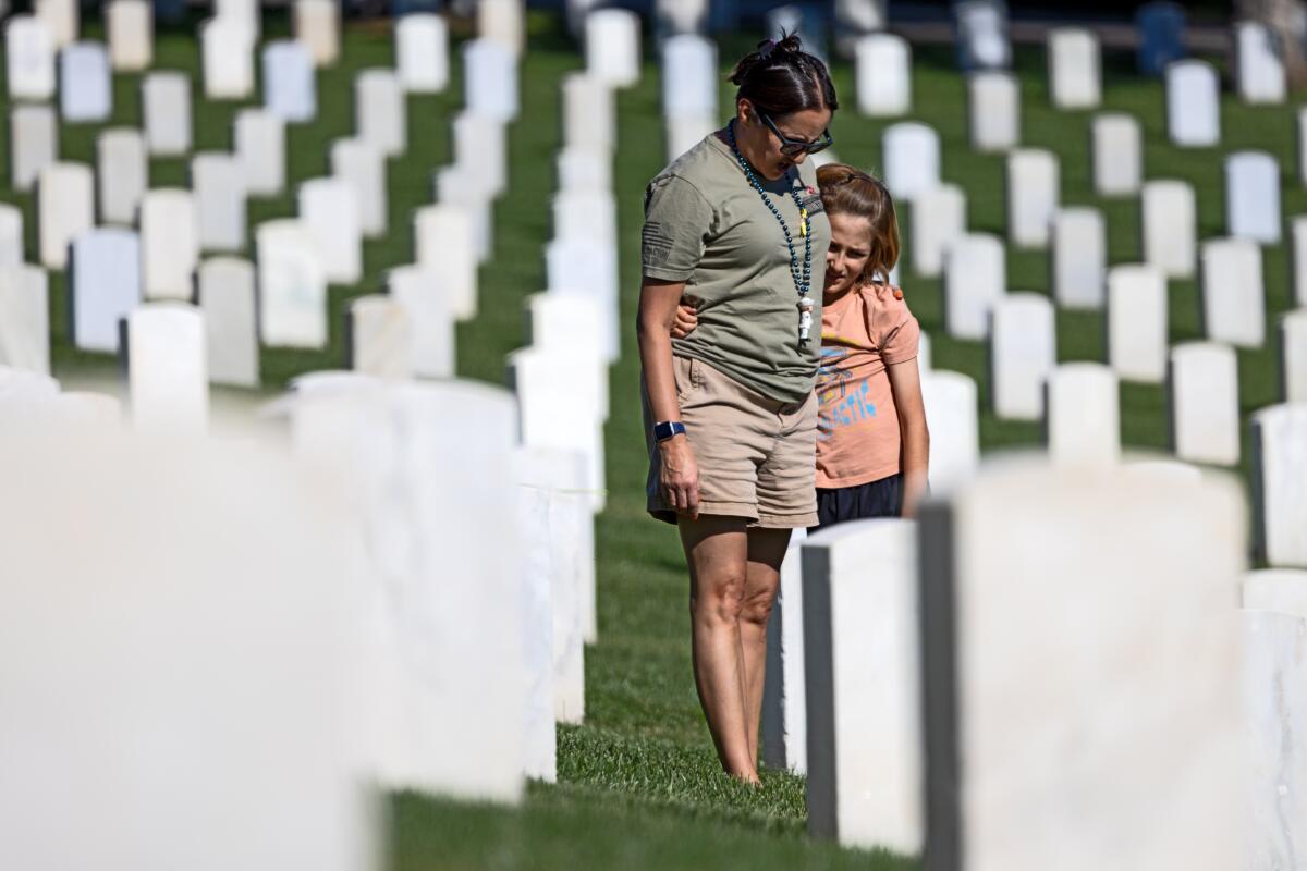 A woman and her son stand among grave markers
