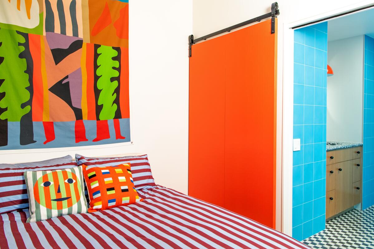 A bedroom with colorful red and blue and green textiles and red barn door