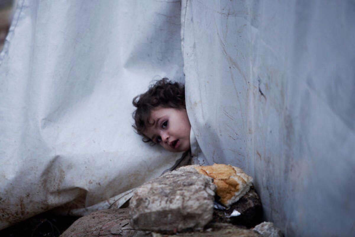 A Syrian girl looks outside her tent at a displacement camp in Azaz, Syria.