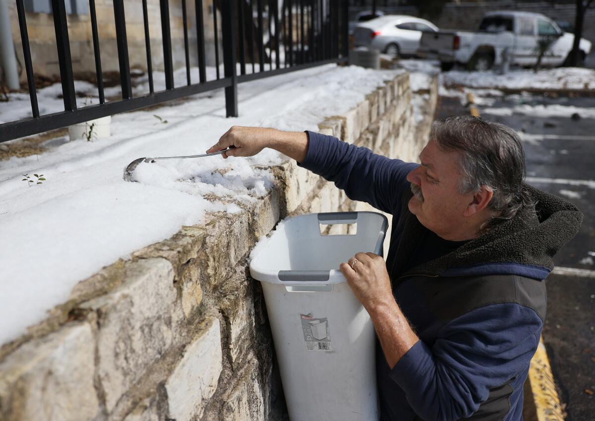 A man in Texas scrapes snow into a kitchen trash can 