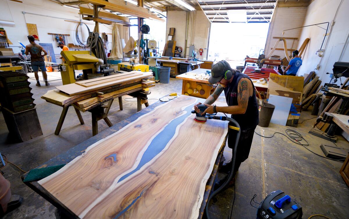 Mat Phelan, production manager at San Diego Urban Timber in Chula Vista, sands a custom dining table.