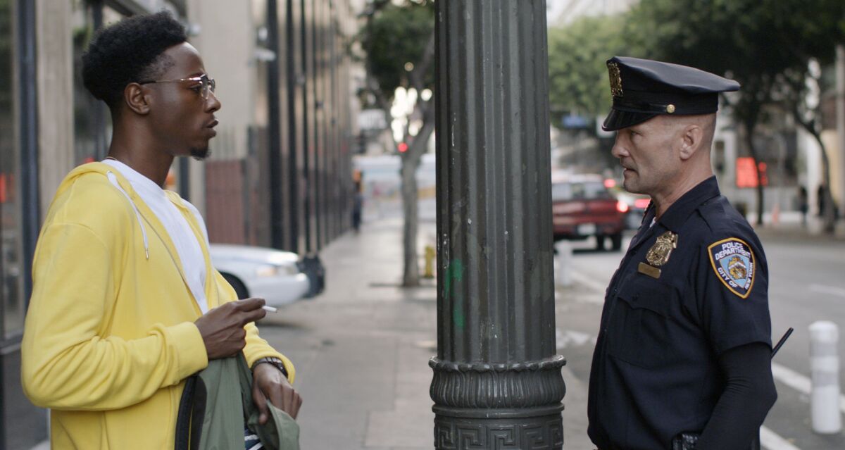 A Black man and a white cop stand facing each other on a city sidewalk