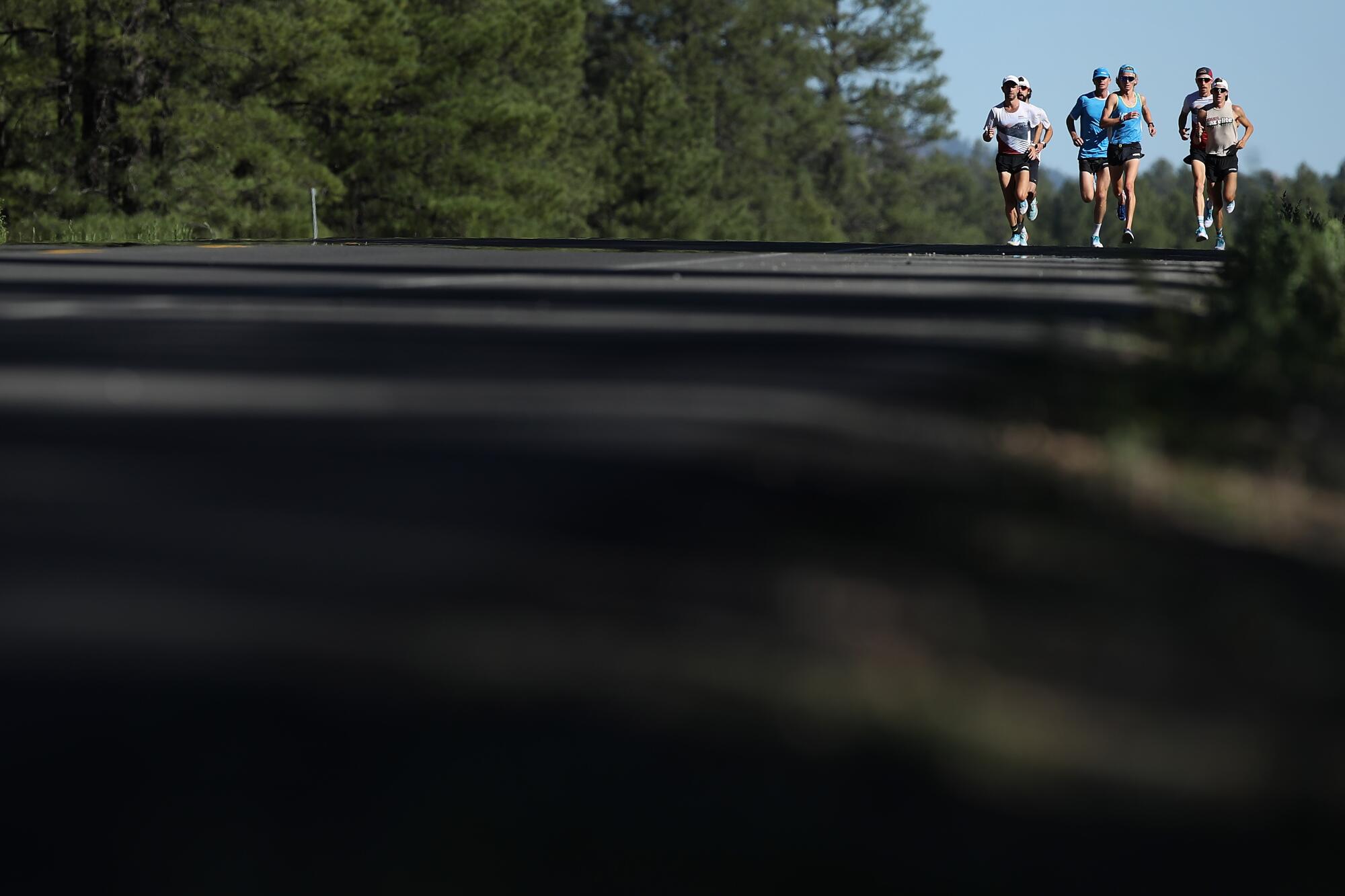 A group of runners from New Zealand train on a road in Flagstaff.