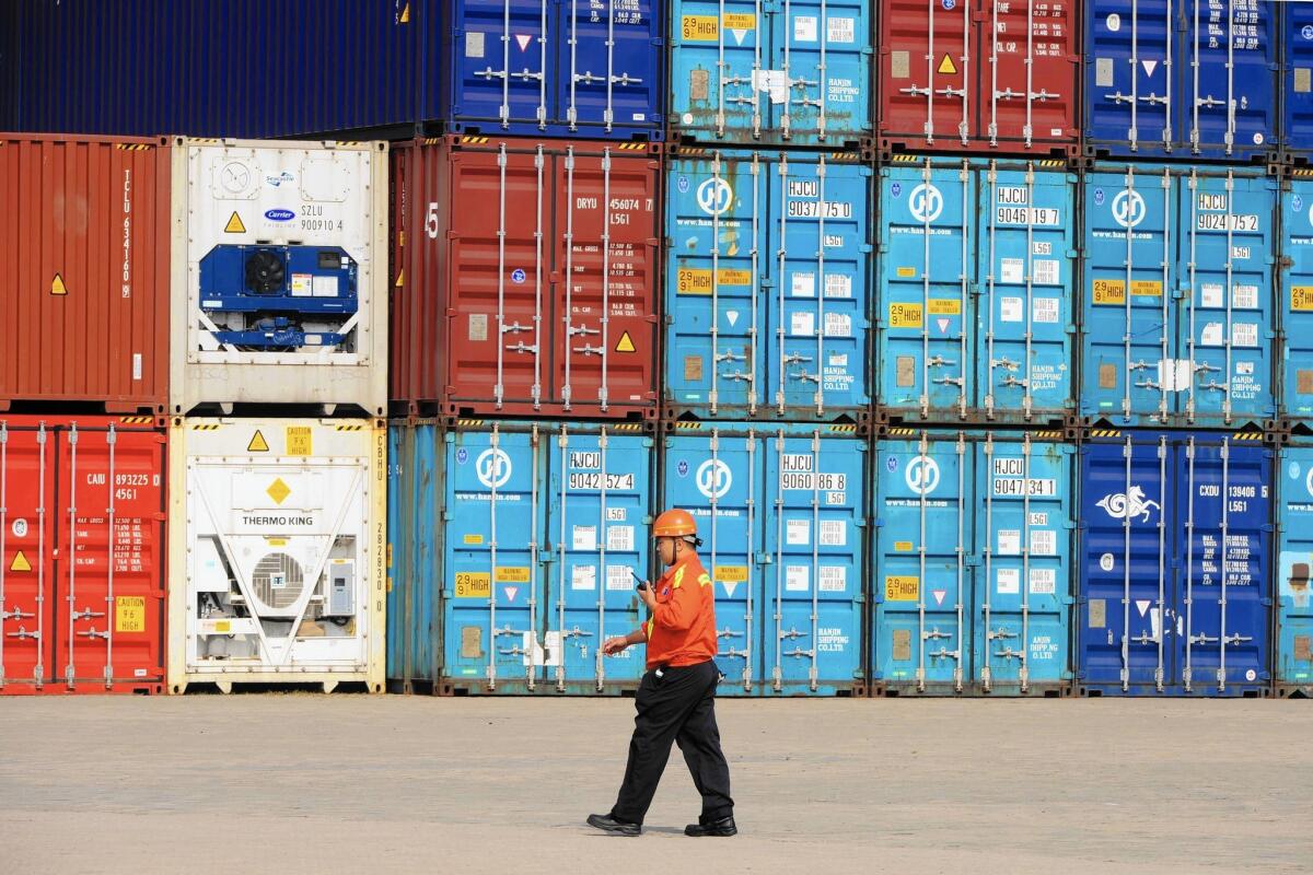 A worker walks past containers waiting to be transported in a port in Qingdao, China.