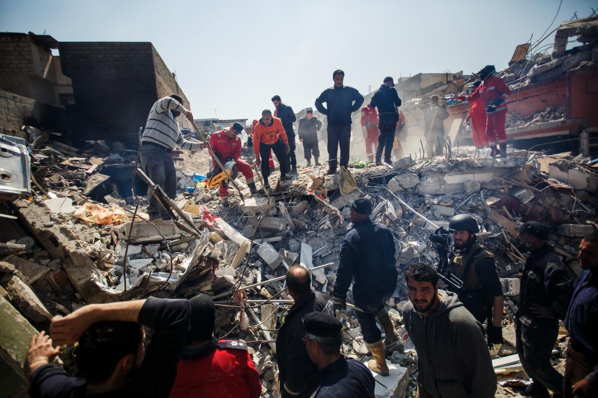 Local residents help Iraqi civil defense force members recover corpses trapped in the rubble of a home destroyed after coalition air strikes in the al-Jadida neighborhood of Mosul.