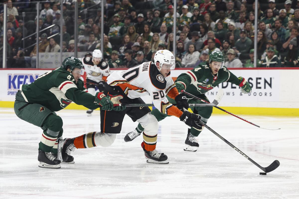 Ducks right wing Brett Leason, center, controls the puck between Minnesota's Declan Chisholm and Jon Merrill.