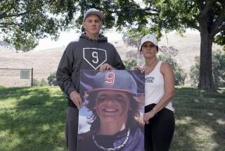 Padrig and Gina Fahey hold a photo of their son, Braden, 12, as they stand for a portrait in California on Wednesday, Sept. 6, 2023. Braden collapsed at football practice in August 2022 and died of a malformed blood vessel in the brain. The Faheys couldn’t understand how Braden’s face appeared on the cover of the book “Cause Unknown,” which was co-published by an anti-vaccine group led by Robert F. Kennedy Jr., or why his name appeared inside it. (AP Photo/Godofredo A. Vásquez)
