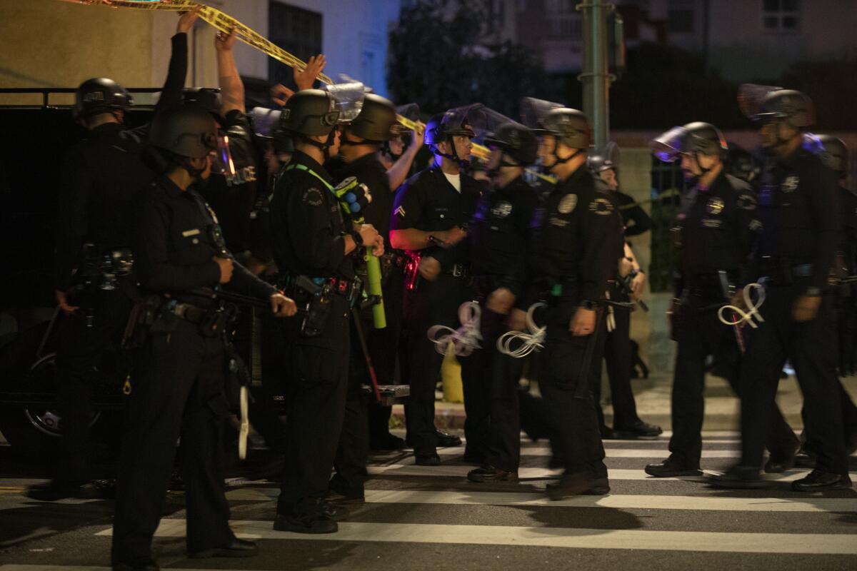 Los Angeles police officers arrive to arrest protesters for curfew violations.