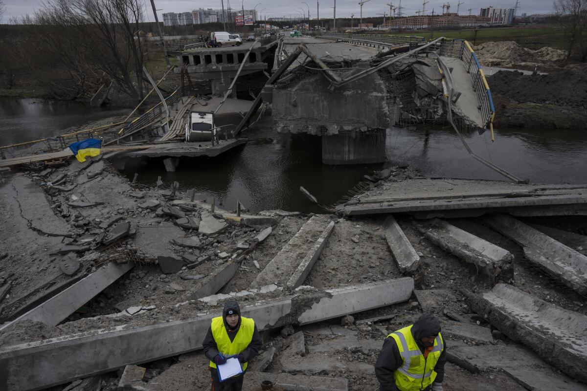 Ukrainian engineers inspect a damaged bridge.