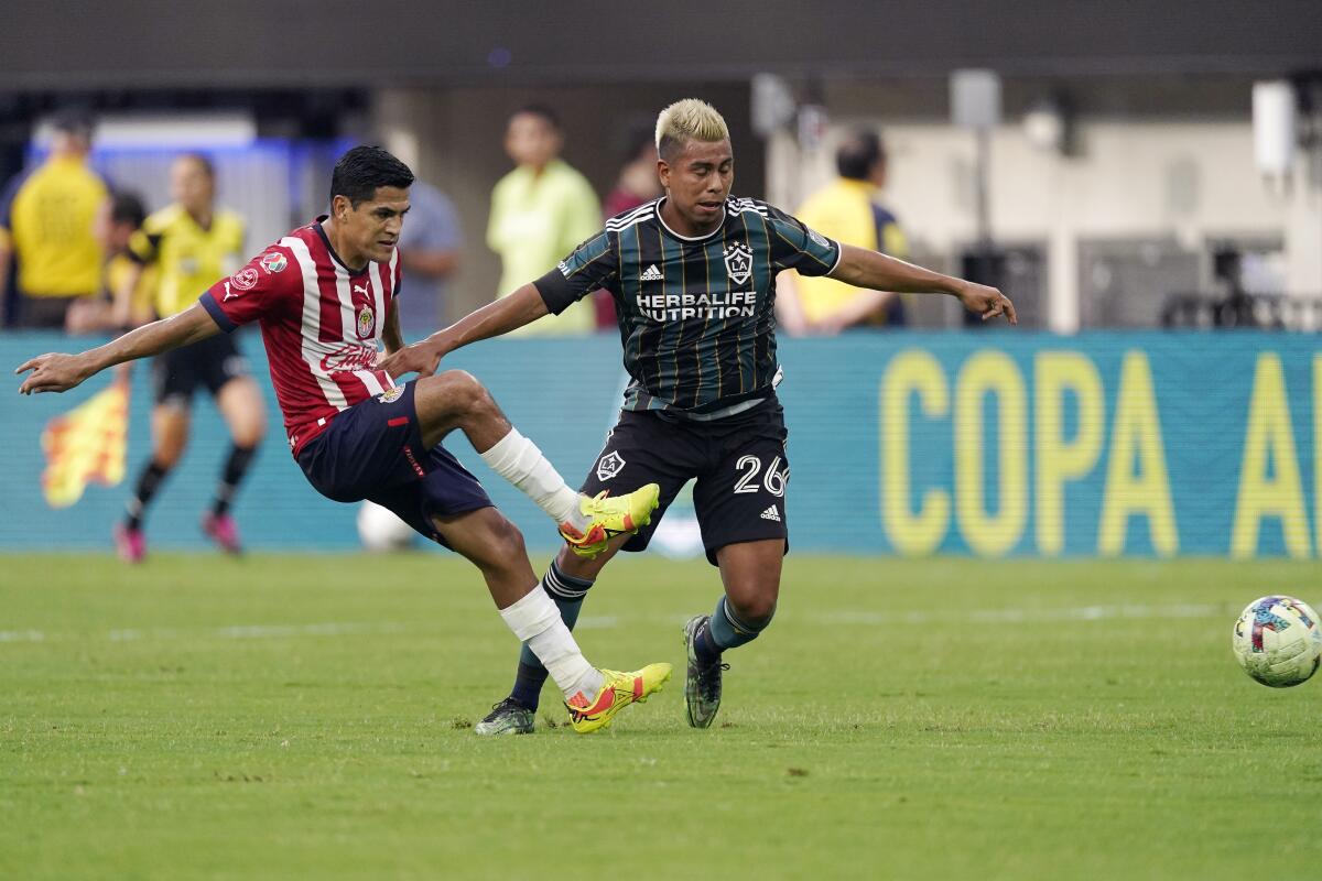 Chivas defender Jesus Sanchez, left, kicks the ball  