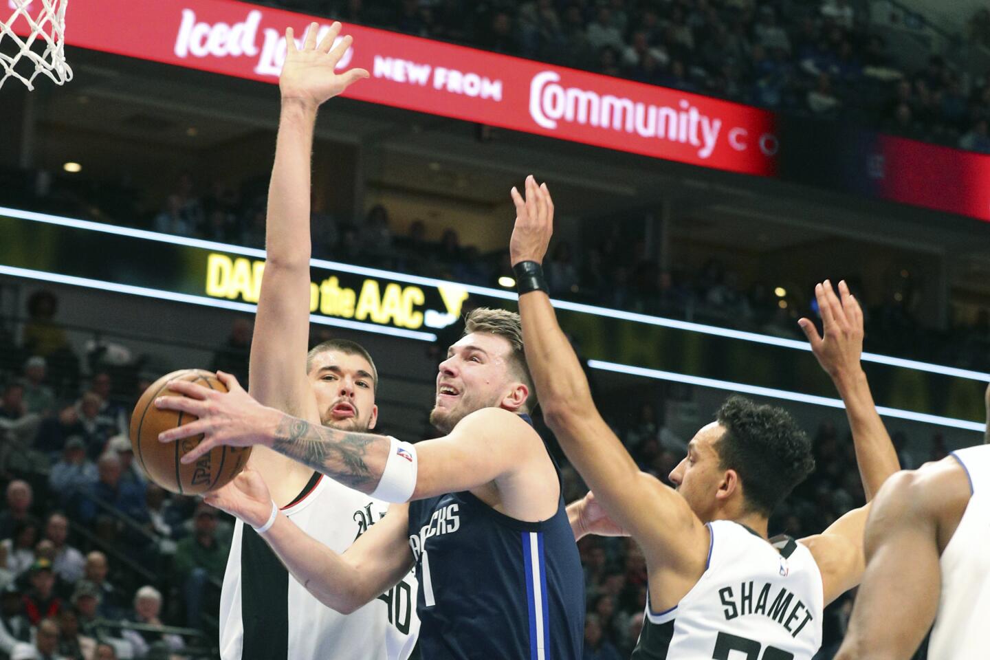 Mavericks forward Luka Doncic (77) drives past a pair of Clippers during a game Jan. 21.