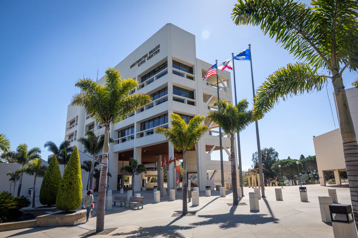 Huntington Beach City Hall, a multistory building flanked by palm trees and flagpoles.