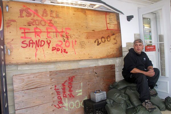 Mark Palazzolo, owner of a bait and tackle shop in Point Pleasant Beach, N.J., sits next to wood he has used to board up his business in major storms over the years.