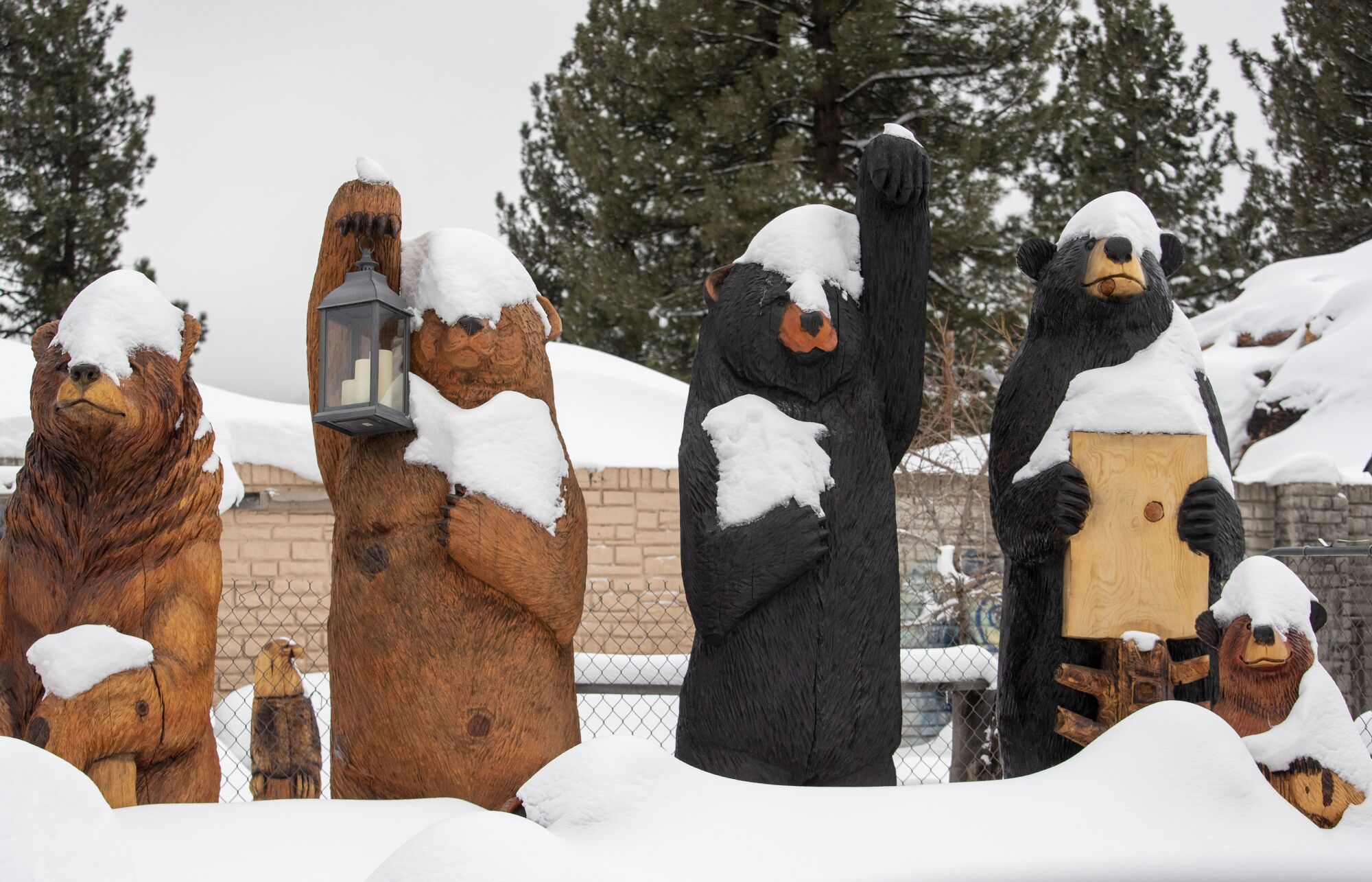 Carved wooden bears are covered in snow in Big Bear.