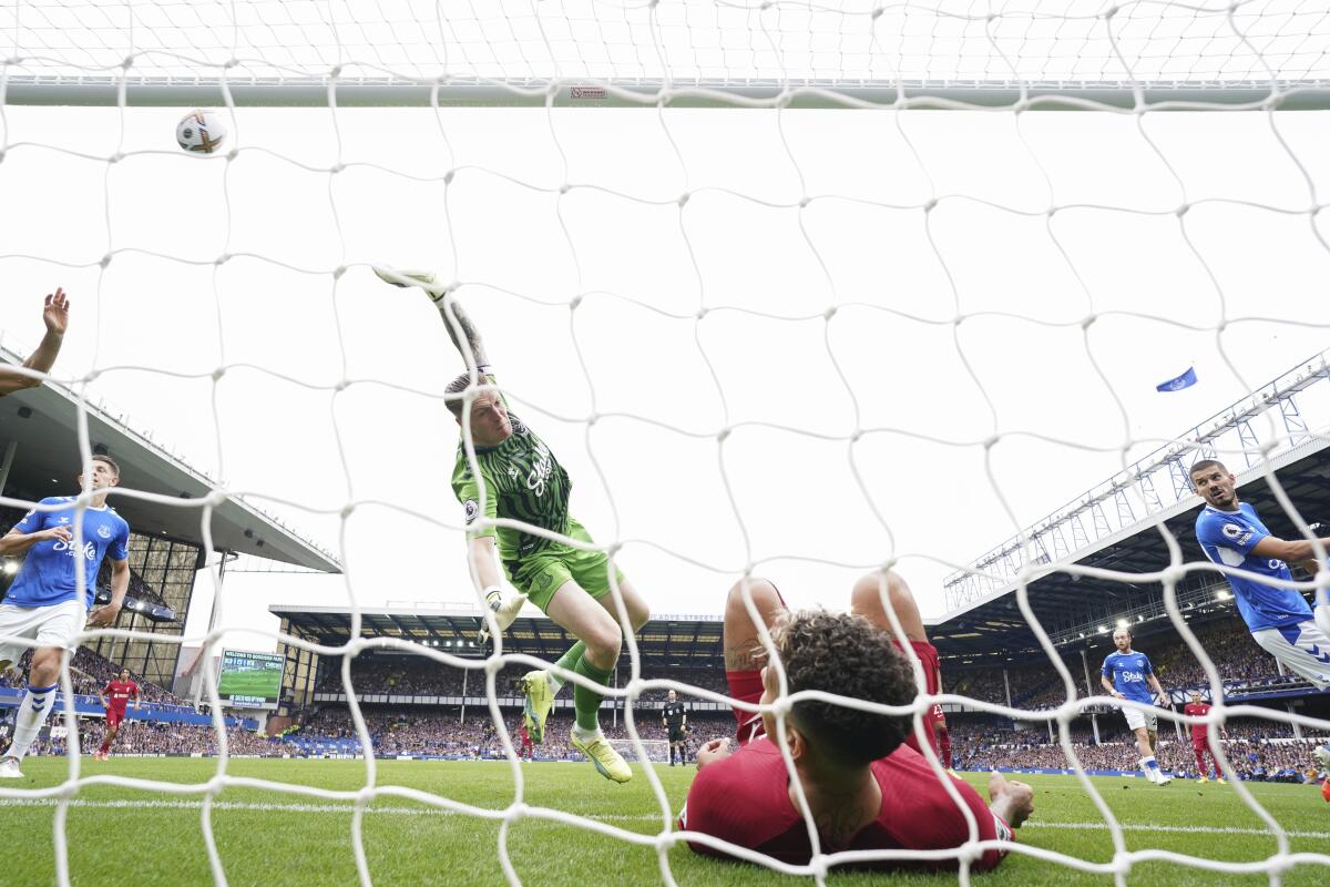 Everton's goalkeeper Jordan Pickford saves a ball as Liverpool's Roberto Firmino falls in the net during the English Premier League soccer match between Everton and Liverpool at Goodison Park, Liverpool, England, Saturday, Sept. 3, 2022. (AP Photo/Jon Super)