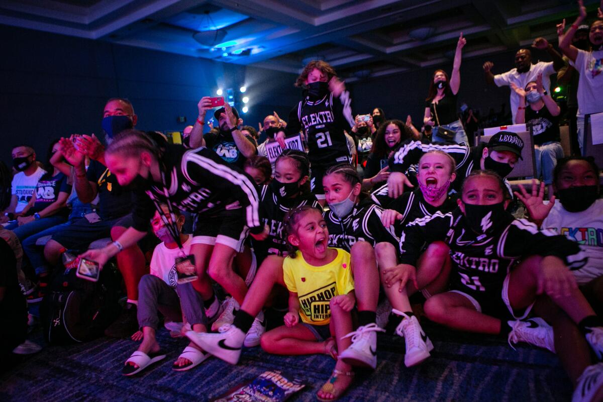 A group of kids seated on the floor and standing. 