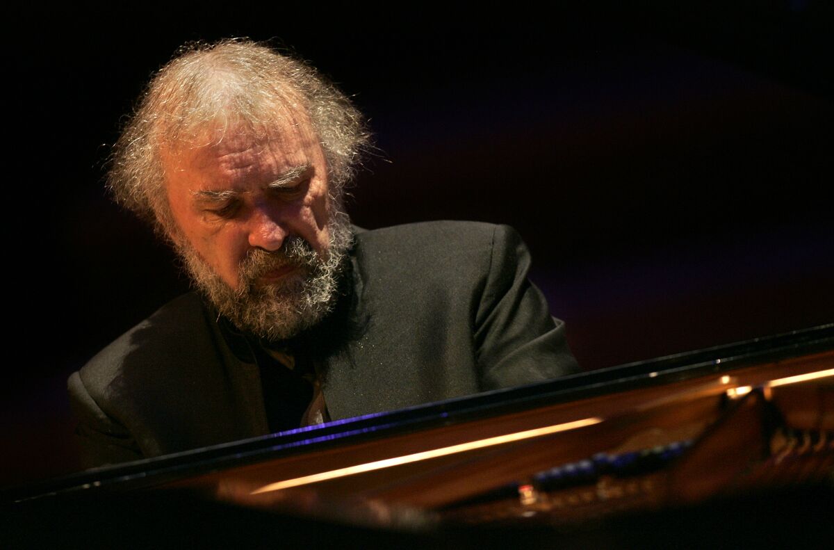 A man seated playing the piano, looking intense.