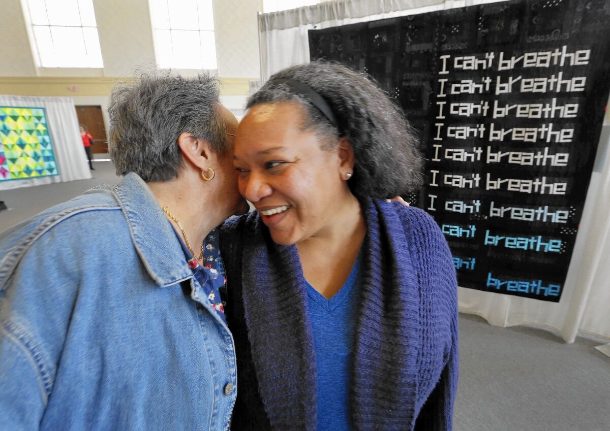 Chawne Kimber, right, whose quilt about Eric Garner won first in improvisational piecing at QuiltCon West, is congratulated by Joan D’Angostino.