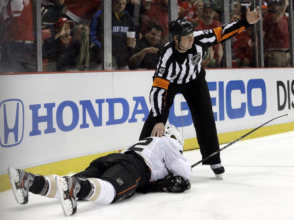 Referee Steve Kozari signals to the bench for a trainer after Ducks defenseman Toni Lydman was checked by Detroit's Justin Abdelkader.