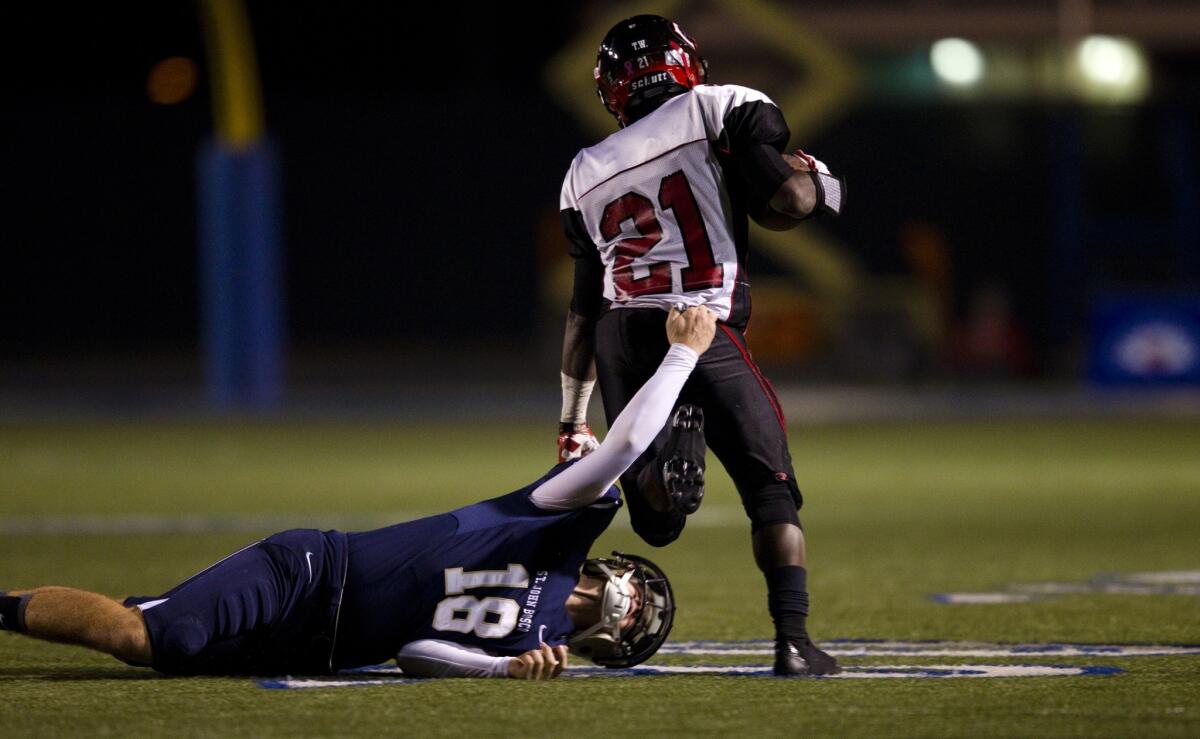 Corona Centennial running back J.J. Taylor is brought down by St. John Bosco's Reid Budrovich during the CIF state championship California Open Division bowl game last year.