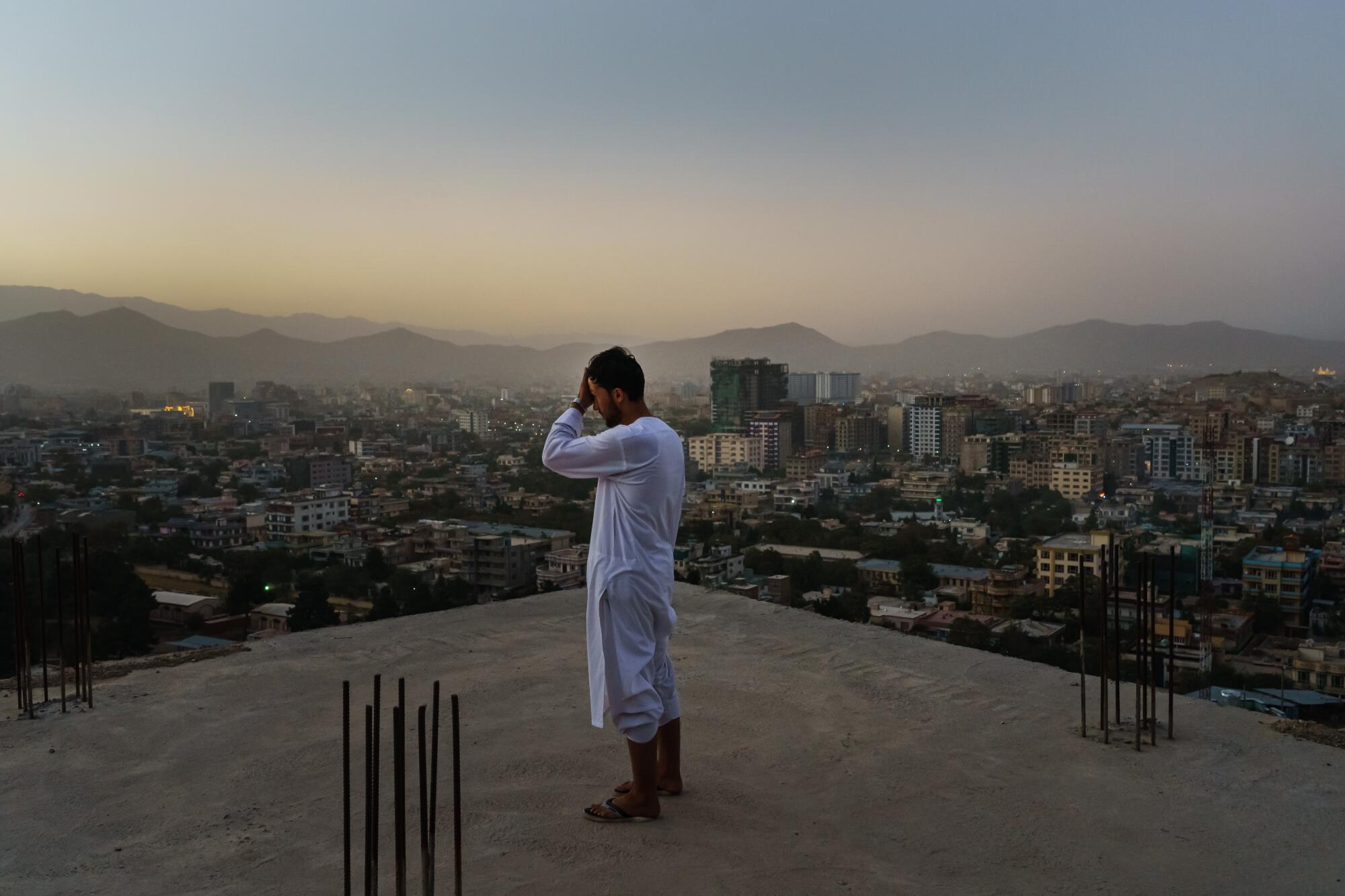 A person stands on an unfinished lot overlooking a city.