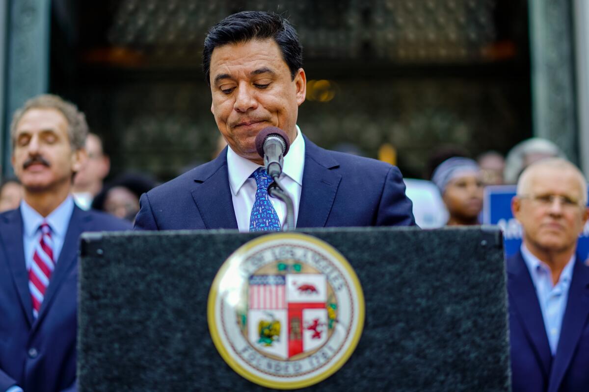 Jose Huizar stands at a lectern with the seal of the city of Los Angeles